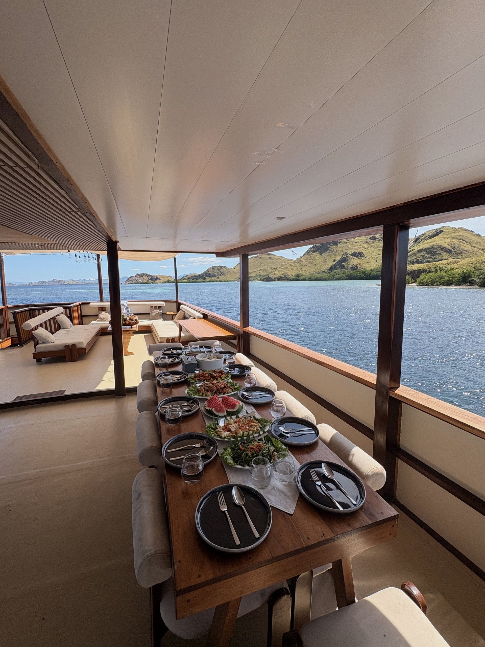 Langer gedeckter Tisch an Deck des Boots, dahinter die Inseln